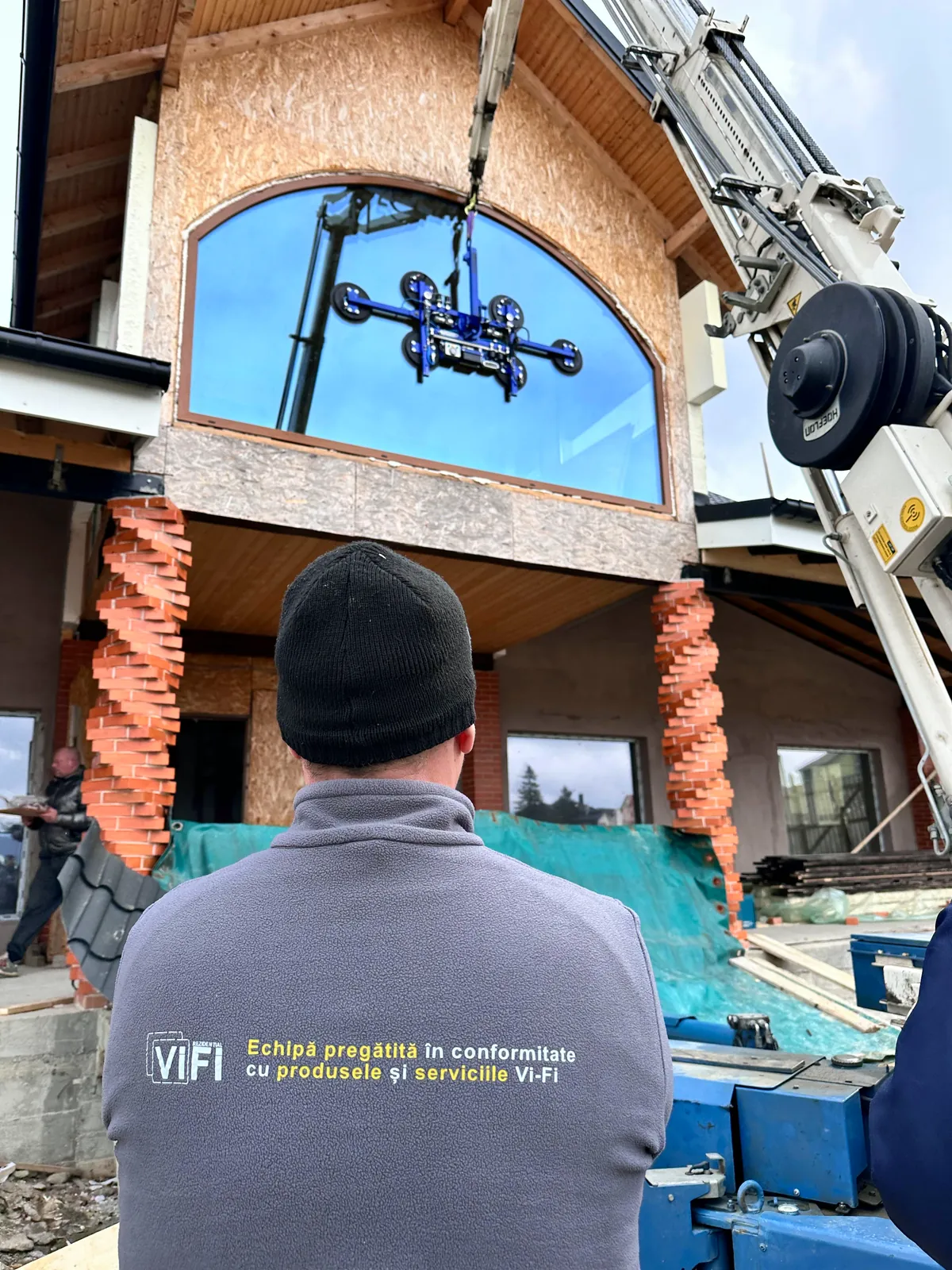 Operator Vi-Fi manevrează robotul la montajul unui geam arcuit