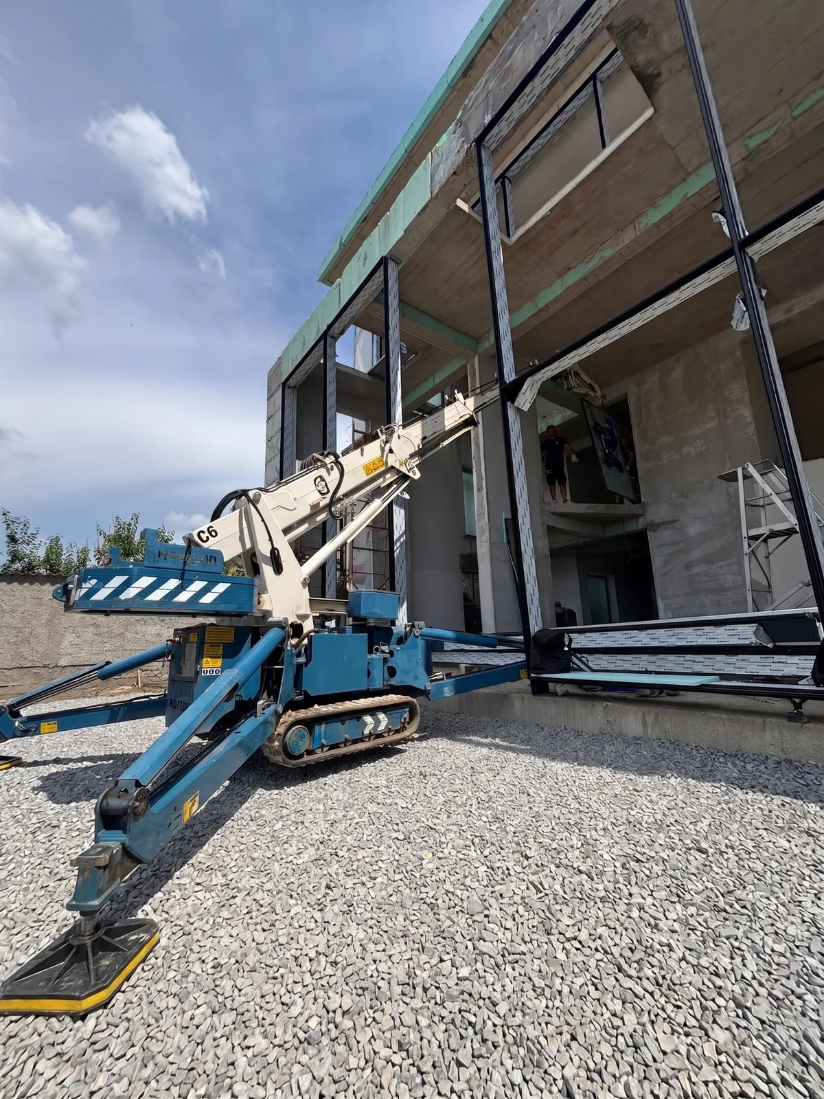 Robotul pe șenile montează un perete de sticlă la o clădire comercială